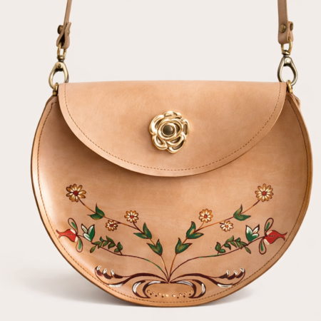 Bolso bandolera artesanal de cuero natural con diseño floral pintado a mano y cierre decorativo en forma de flor.