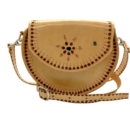 Bolso redondo artesanal de cuero natural con decoración geométrica grabada a mano y correa ajustable.