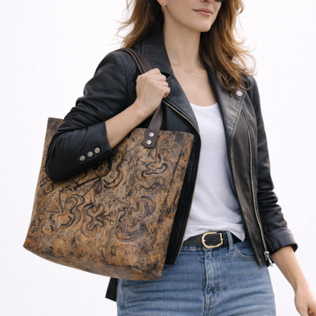 Mujer llevando bolso tote artesanal de cuero marrón con diseño grabado decorativo y asas de cuero oscuro.