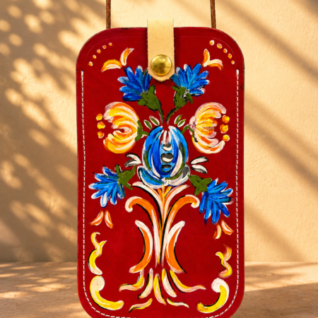 Porta móvil artesanal de cuero Pajarico con diseño floral tradicional pintado a mano sobre fondo rojo.