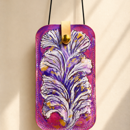 Porta móvil artesanal de cuero Pajarico con diseño de pluma violeta pintada a mano sobre fondo fucsia.